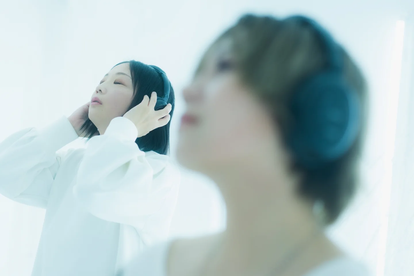 室内でヘッドホンをつけ、音楽に耳を澄ます人たち