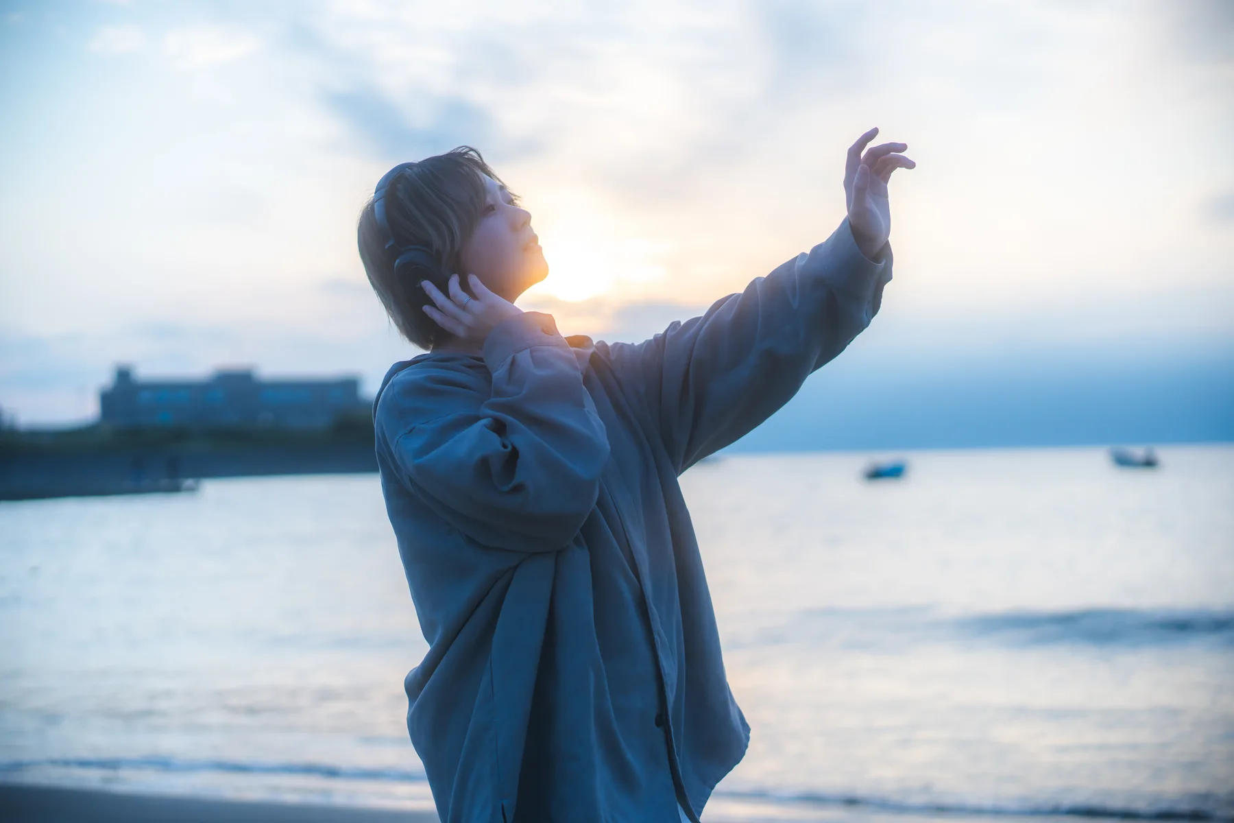 海辺でヘッドホンをつけ、音楽に身を委ねる人
