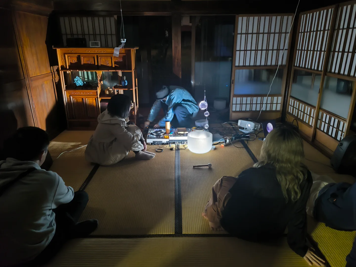 畳の上で作品を囲み、光と音に耳を澄ます鑑賞者たち